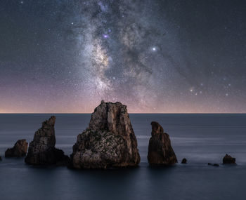 Scenic view of rocks in sea against sky