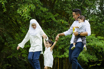 Full length of father with daughter against trees