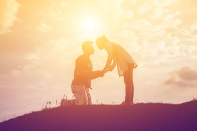 Silhouette couple standing against sky during sunset