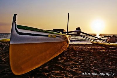 Boat moored on beach against sky during sunset