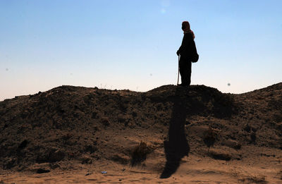 Full length of silhouette man standing on rock against sky