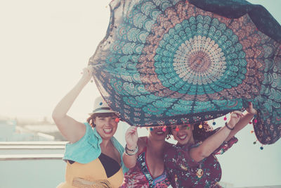 Happy female friends holding scarf