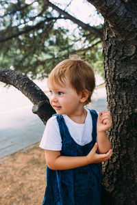 Little girl walks in the garden among beautiful evergreen southern plants