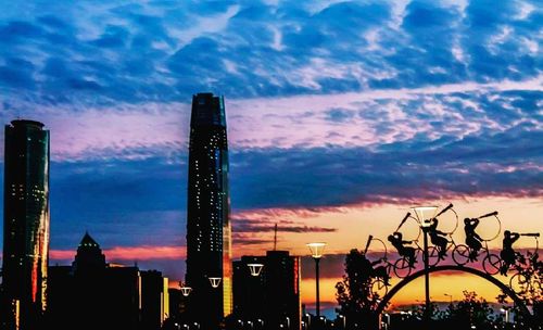 Illuminated city against sky at sunset