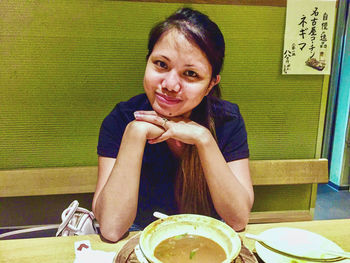 Portrait of a smiling young woman sitting on table