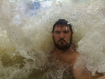 Portrait of shirtless man swimming in sea