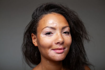 Close-up of young woman against gray background