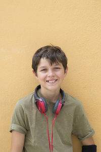 Portrait of boy with headphones against beige wall