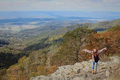 Young woman with arms outstretched standing on mountain