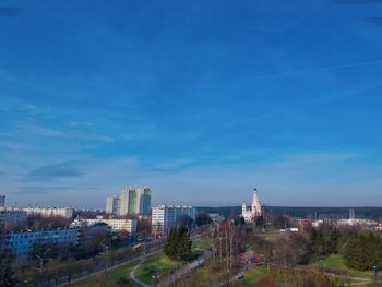 Aerial view of buildings in city against blue sky