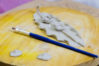 Close-up of paintbrush and clay product on wooden table