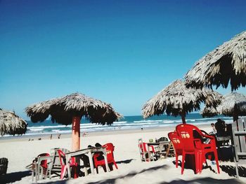 Panoramic view of people on beach against clear blue sky