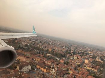 Airplane flying over cityscape against sky