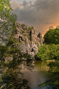 Rock formation amidst trees against sky during sunset