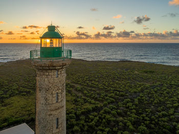 Lighthouse by sea against sky