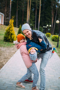 Father and two children walk in nature in autumn, spend time together, have fun.