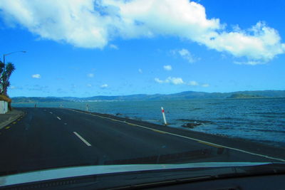 Road by sea against sky seen through car windshield