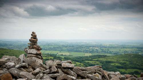 Stack of rocks on landscape against cloudy sky