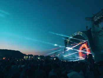 Crowd at music concert against sky at night