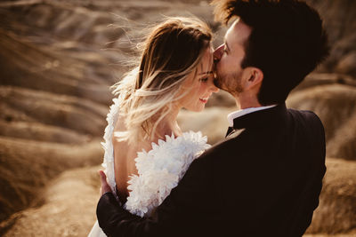 Man in suit embracing and kissing woman on forehead during wedding celebration in bardenas reales natural park in navarra, spain