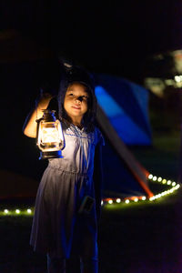 Girl holding illuminated lantern at night