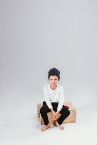 One caucasian cute preschool boy sitting on big box isolated on white studio background, copyspace. 