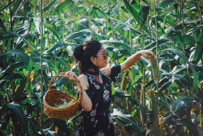 Full length of woman standing by plants in field