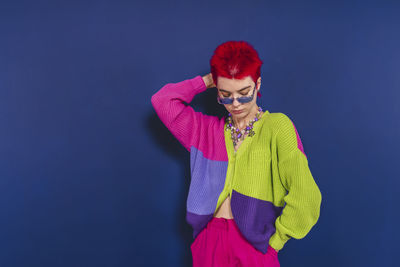 Woman looking away while standing against blue background