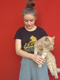 Side view of young woman with cat against yellow background