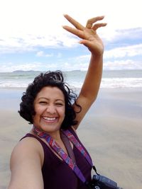 Portrait of smiling young woman at beach against sky