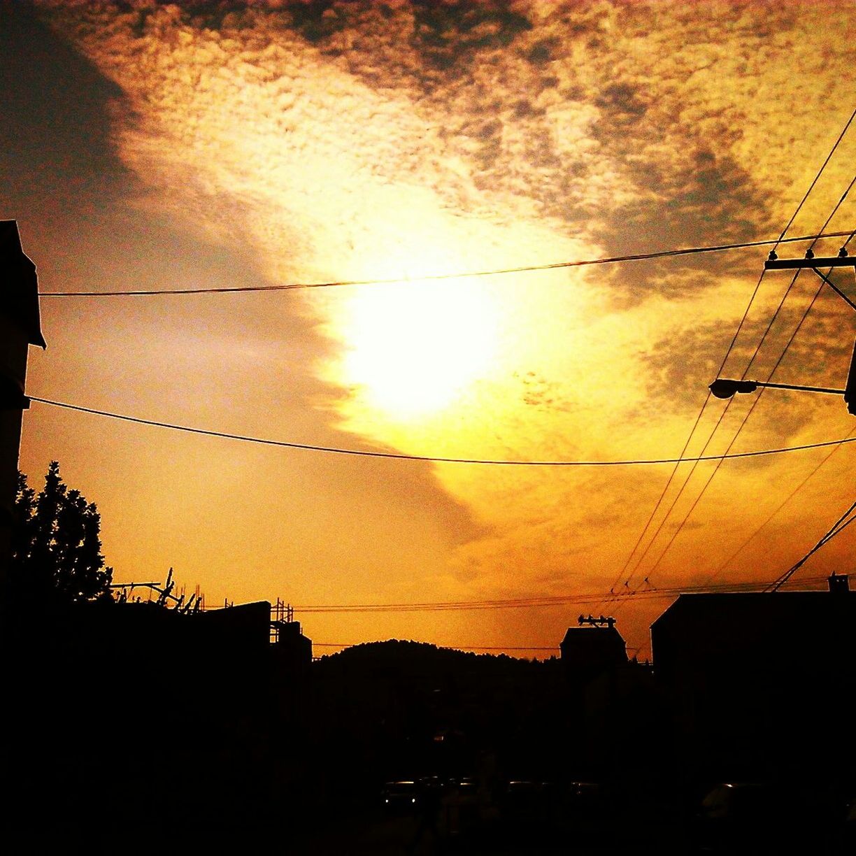 sunset, silhouette, architecture, built structure, power line, sun, building exterior, sky, orange color, electricity pylon, cable, low angle view, sunlight, connection, electricity, cloud - sky, house, building, power supply, nature