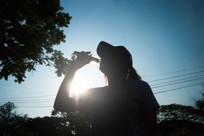 Side view of silhouette man photographing against sky during sunset