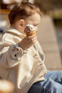 Little adorable boy sitting outdoors and eating ice cream. lake, water and sunny weather. 