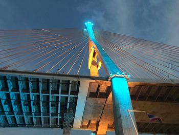 Low angle view of illuminated bridge against buildings in city