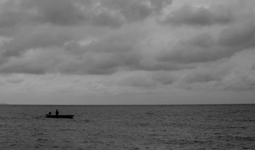 Silhouette people in sea against sky