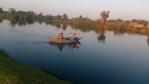 People in boat on lake against sky