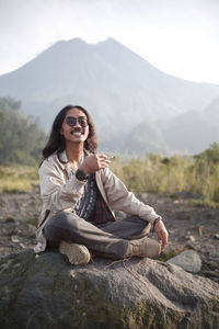 Relax and enjoy a cigarette on a rock with a view of mount merapi