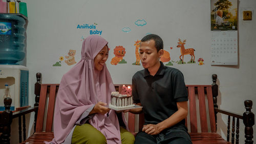 Husband blowing birthday candles given by his wife as a surprise