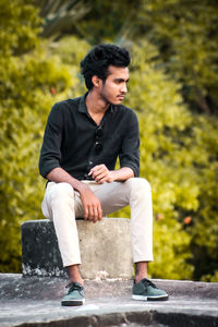 Young man sitting on retaining wall