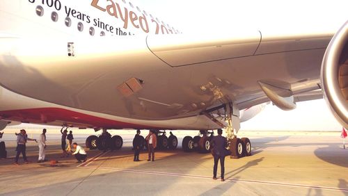 People at airport runway against sky