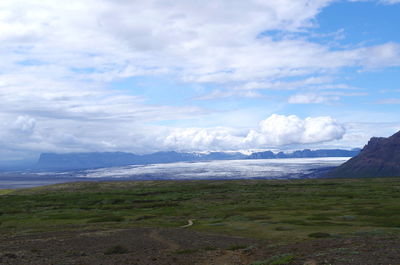 Scenic view of sea and mountains against cloudy sky