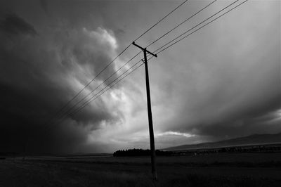 Low angle view of electricity pylon on field against sky