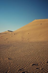 Sand dunes in desert against clear blue sky