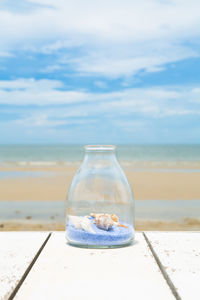 Water bottle on table at beach against sky