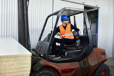 Worker on forklift in factory turning round