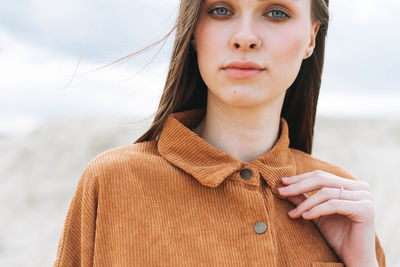 Fashion beauty portrait of young woman in brown organic velvet shirt on desert background