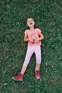 Little girl laying playing on grass enjoying summer day. happy child playing in the field