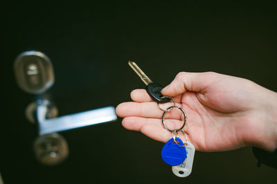 Cropped hand of woman holding key against door