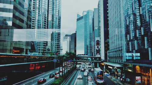 Traffic on road amidst buildings in city seen through glass window