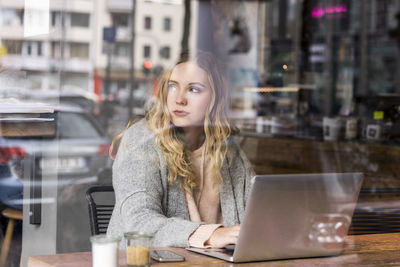 Portrait of young woman working on laptop in a coffee shop